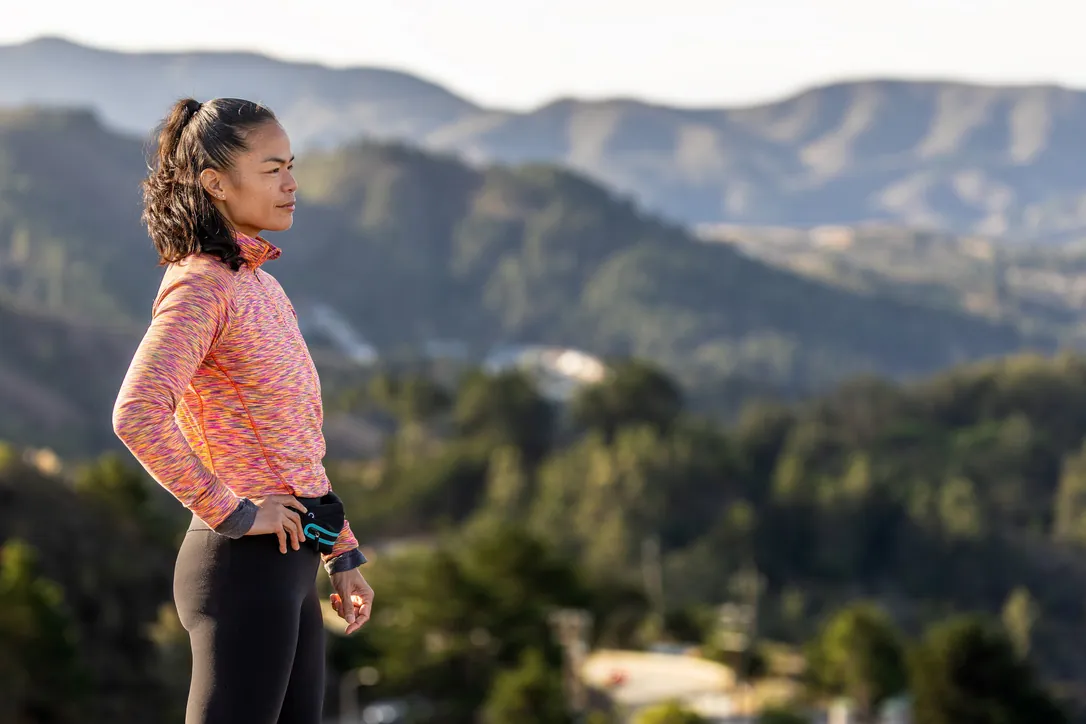 Femme en tenue de randonnée contemplant les collines boisées des Pyrénées-Orientales lors d'une pause randonnée