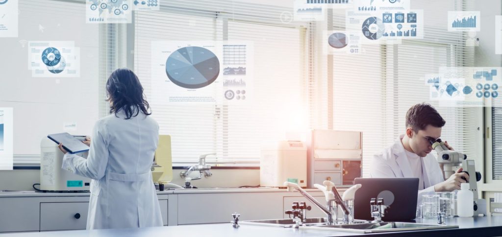 Deux chercheurs en laboratoire analysent des données scientifiques via graphiques et statistiques