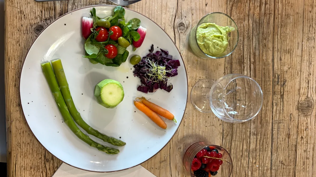 Assiette de reprise alimentaire : mâche, tomates cerises, radis, chou rouge, courgette, asperges et crème d'avocat