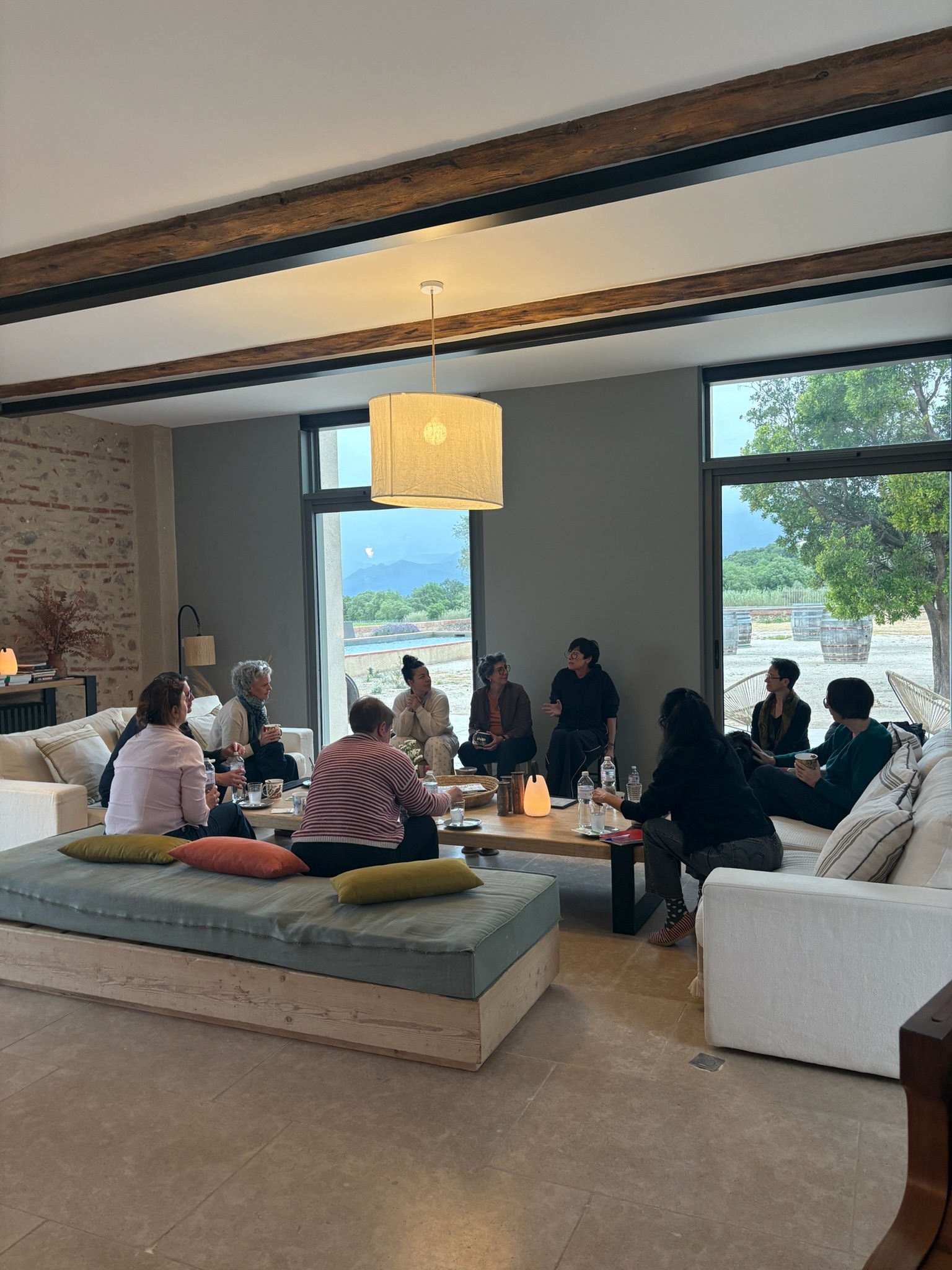 Un groupe assis en cercle dans un salon lumineux ouvert sur le paysage