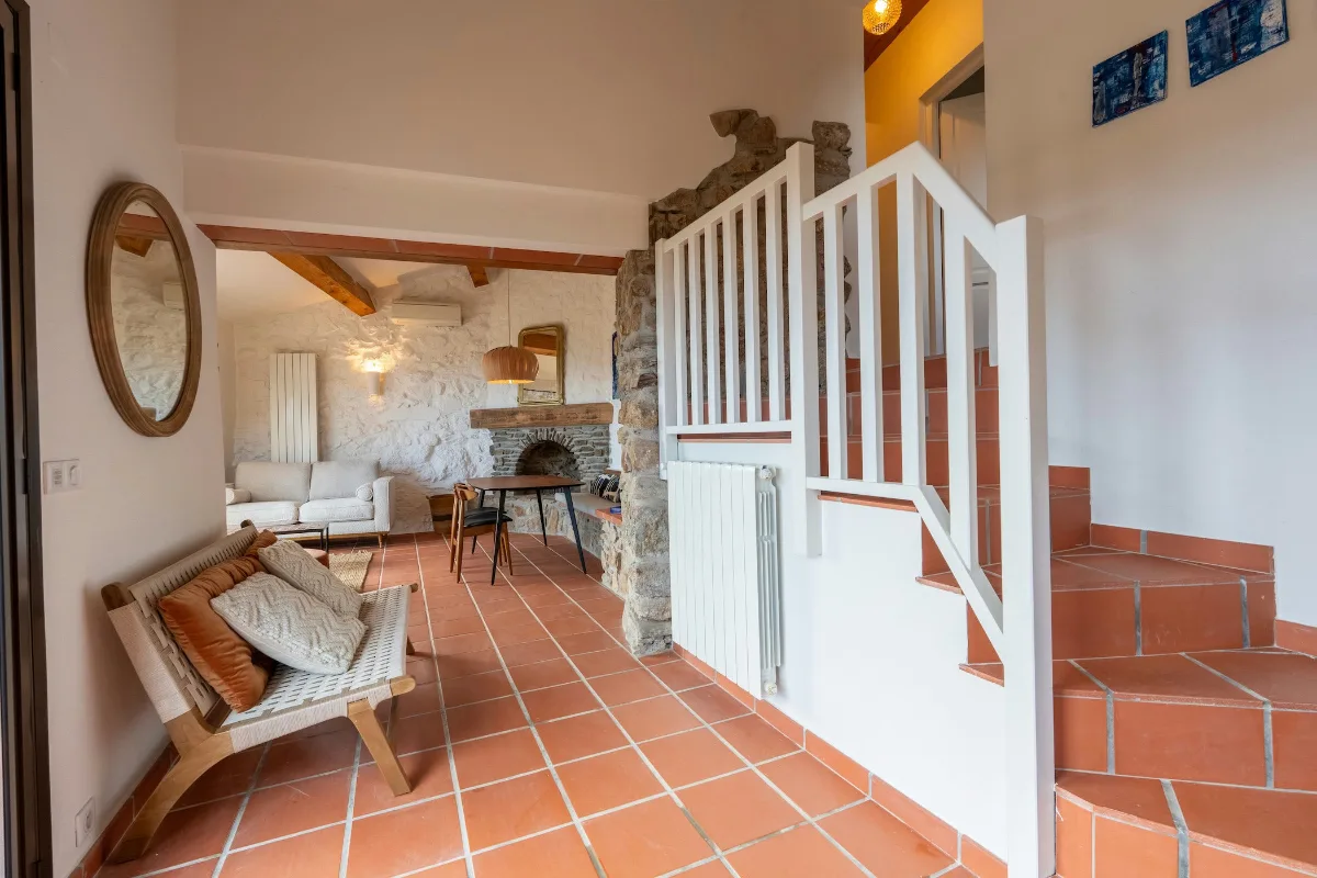 Intérieur aux murs de pierre, escalier et mobilier de bois clair