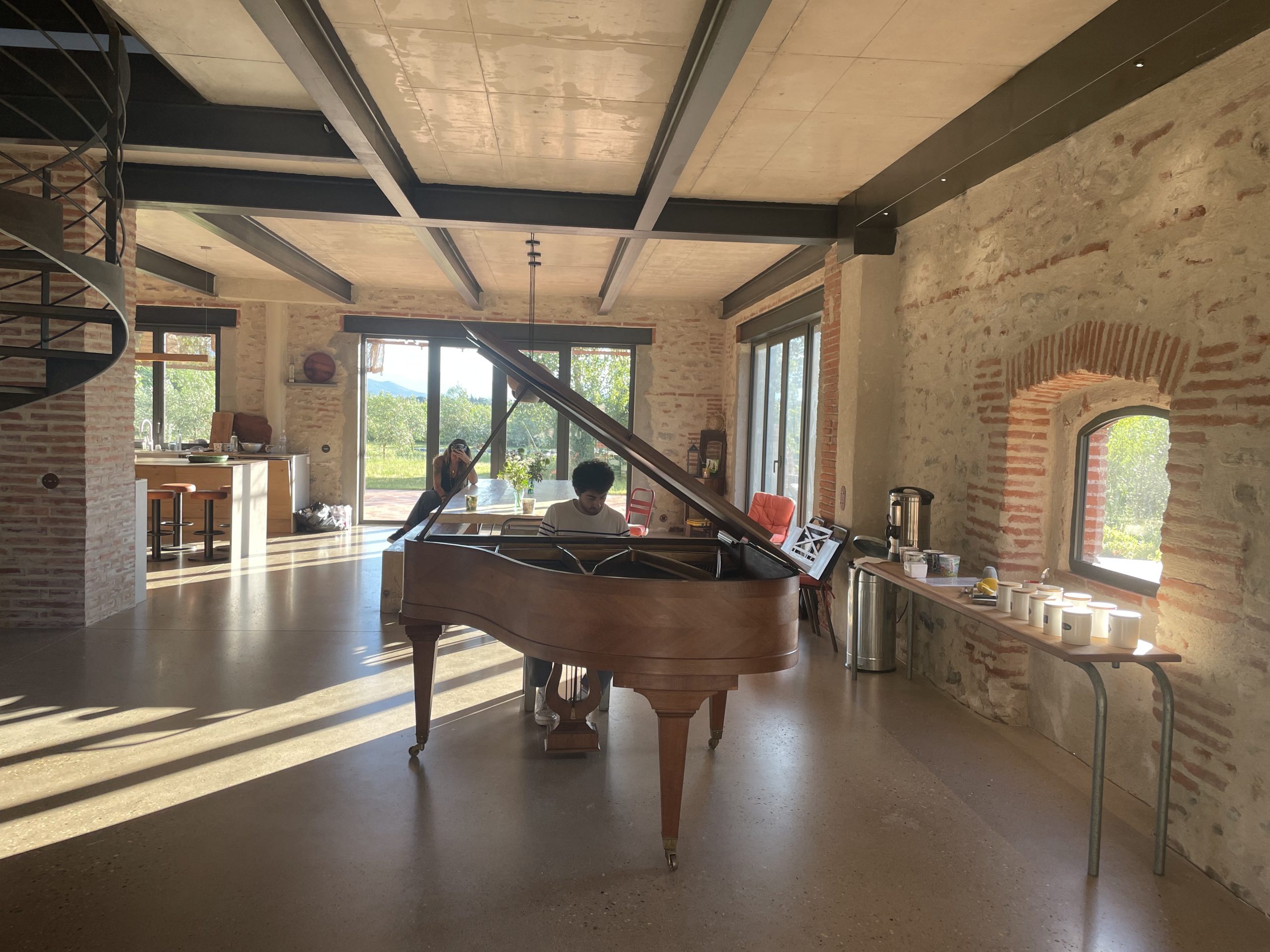 Un piano à queue dans une grande salle claire, le bar à infusions le long du mur