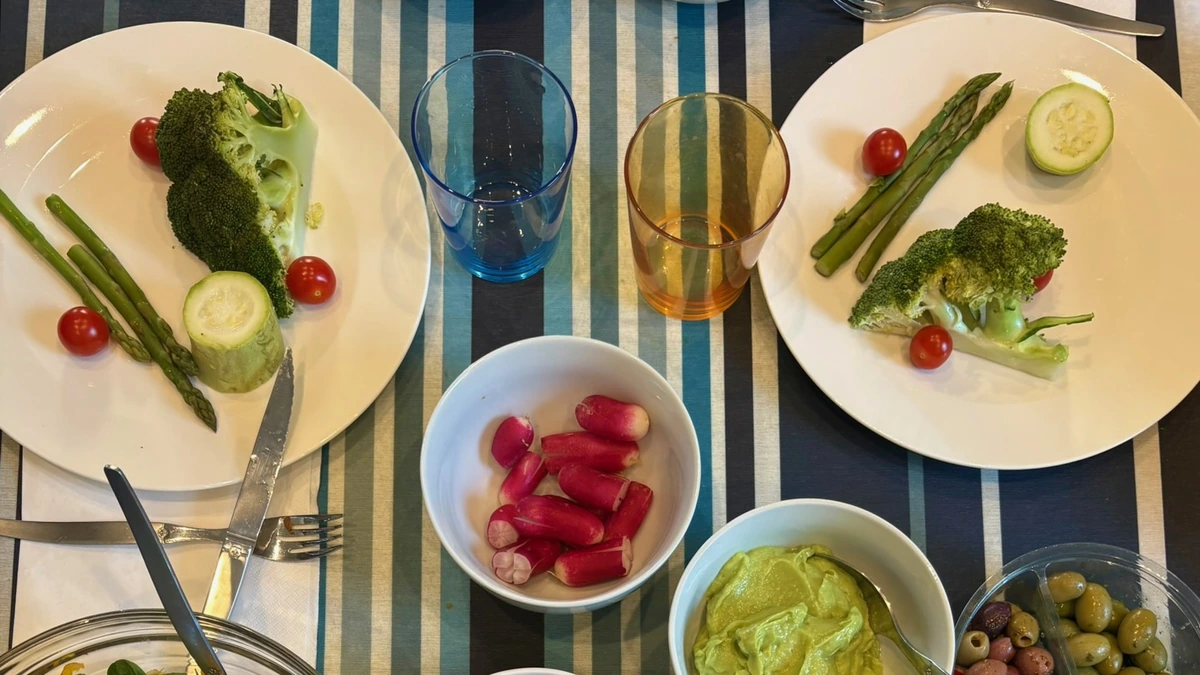 Table de reprise dressée : assiettes de légumes vapeur, bols de fruits rouges, crème d'avocat et olives.