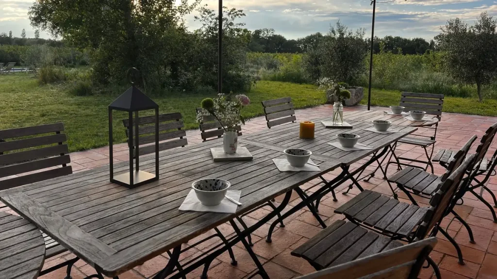 Longue table en bois dressée de bols et de fleurs sous une pergola, au soleil couchant, pendant un séjour de jeûne