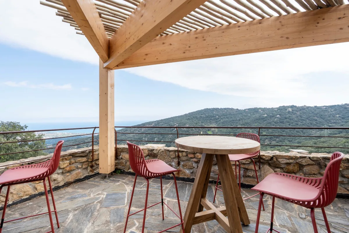 Table et chaises installées sur une terrasse ouverte face aux collines