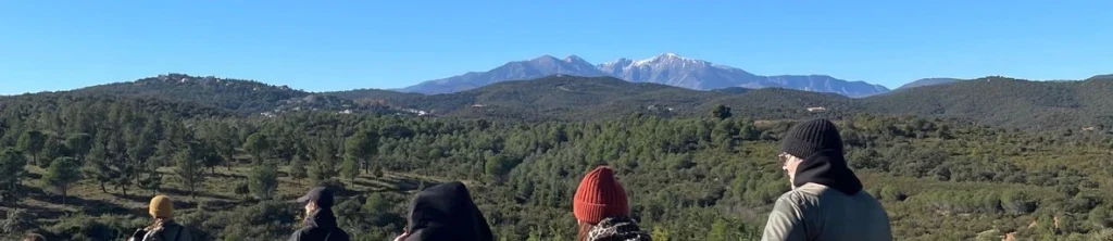 Sommet enneigé du Canigou dominant la vallée, vu par un groupe de randonneurs de dos