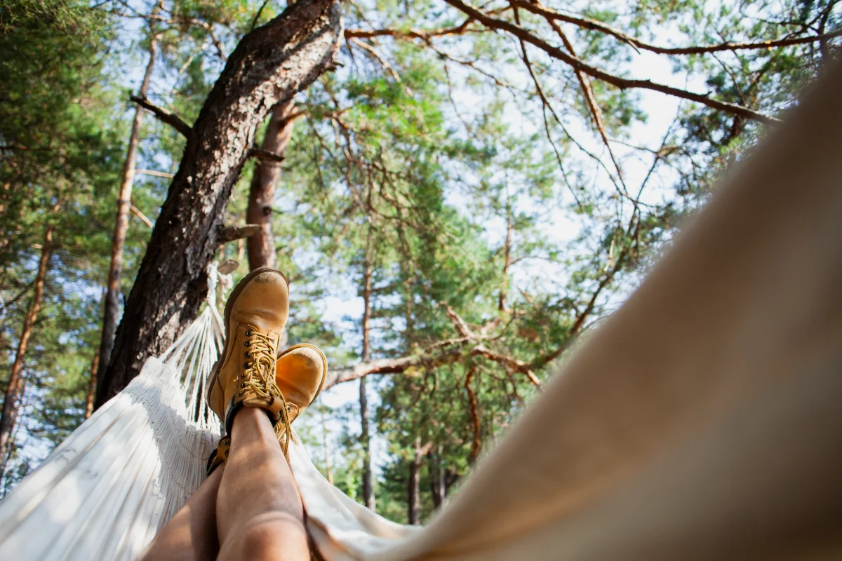 Détente dans un hamac en forêt, pieds au premier plan